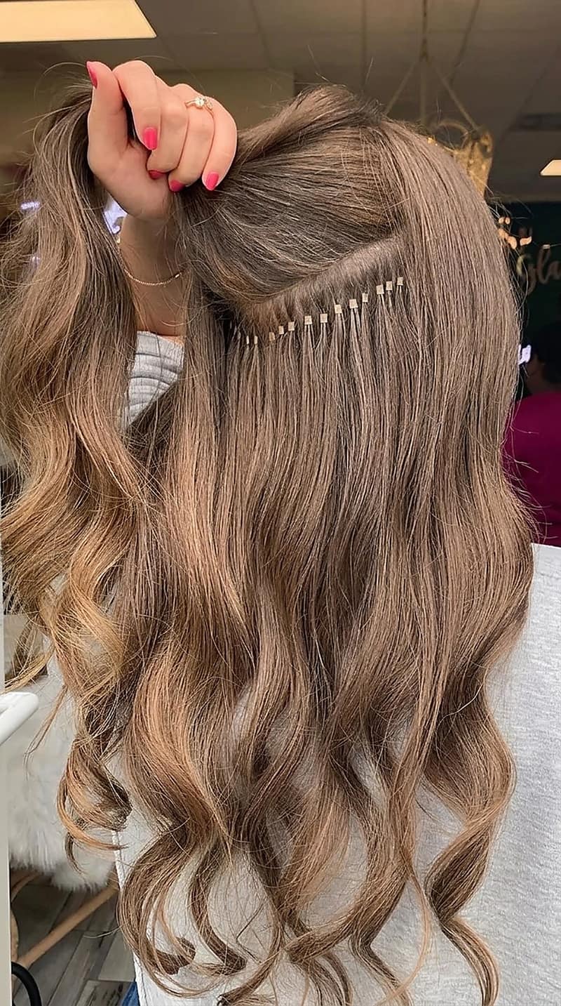 I-tip extensions being applied to brown hair